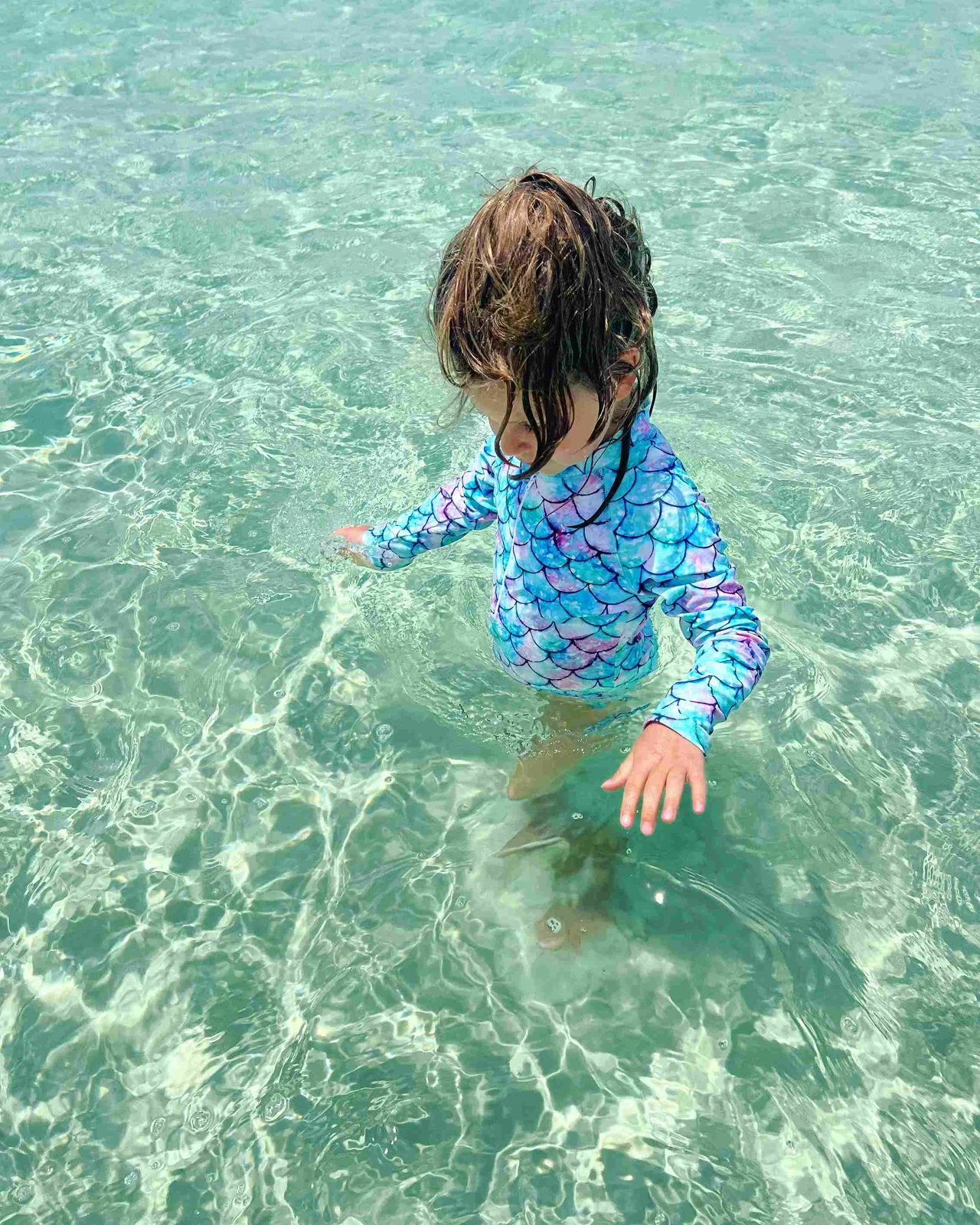 A child enjoying a swim in clear coastal water